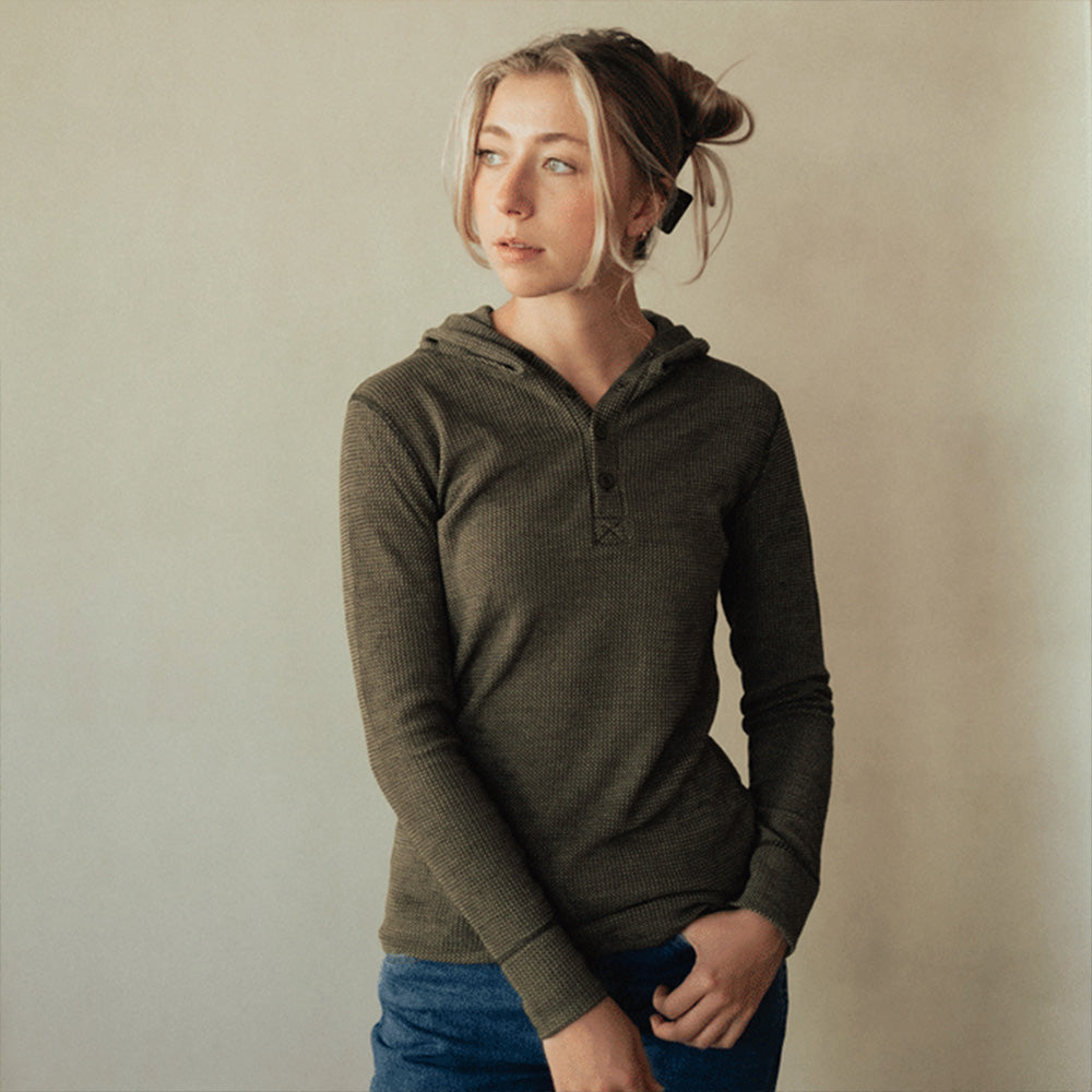 A woman wearing a green American made Duckworth merino wool waffle knit hoody.
