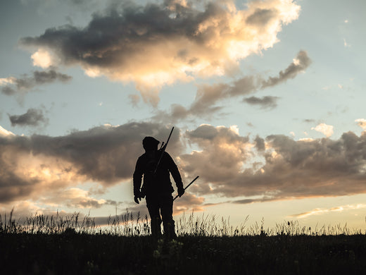 A rancher hiking through a field.