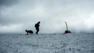 A man and his dog hiking in the snow. 
