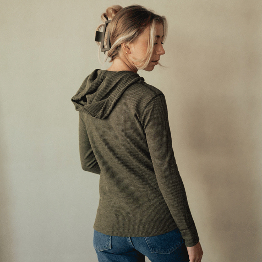A woman wearing a green American made Duckworth merino wool waffle knit hoody.