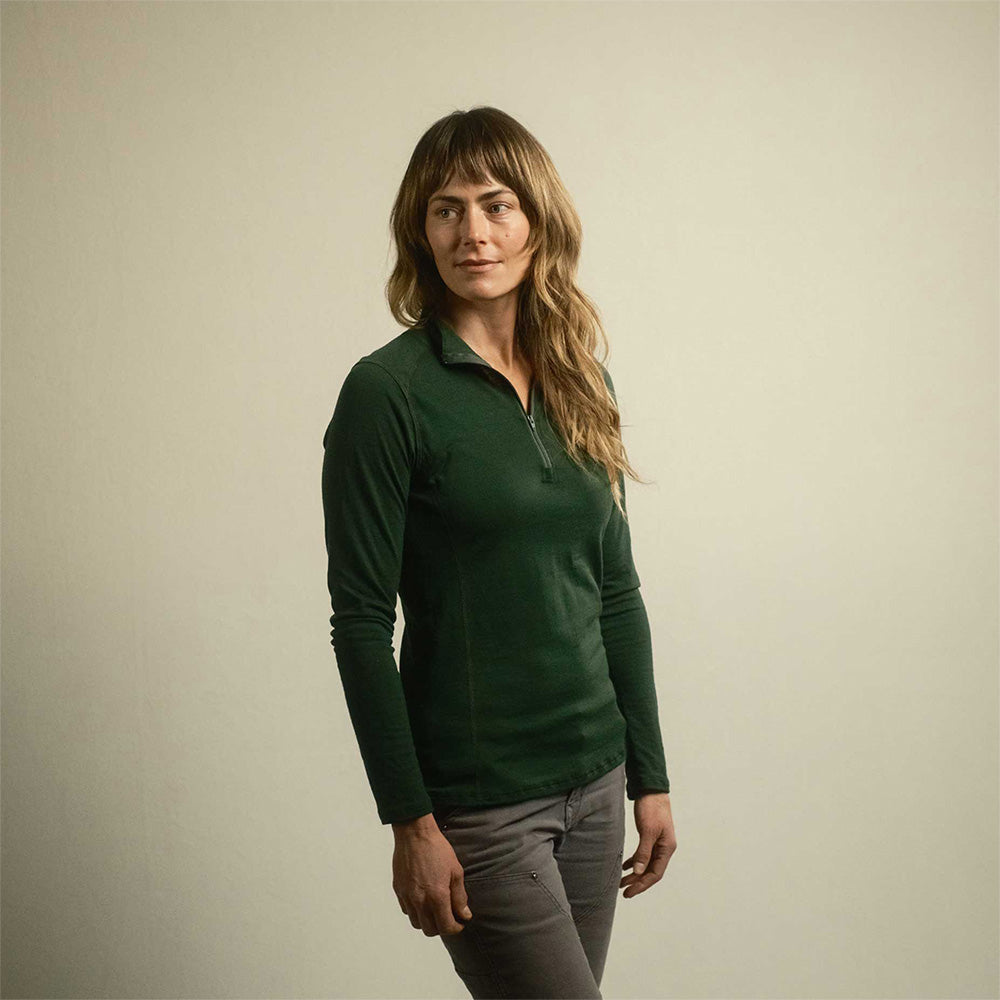 A woman wearing a green American made Duckworth merino wool quarter zip base layer.