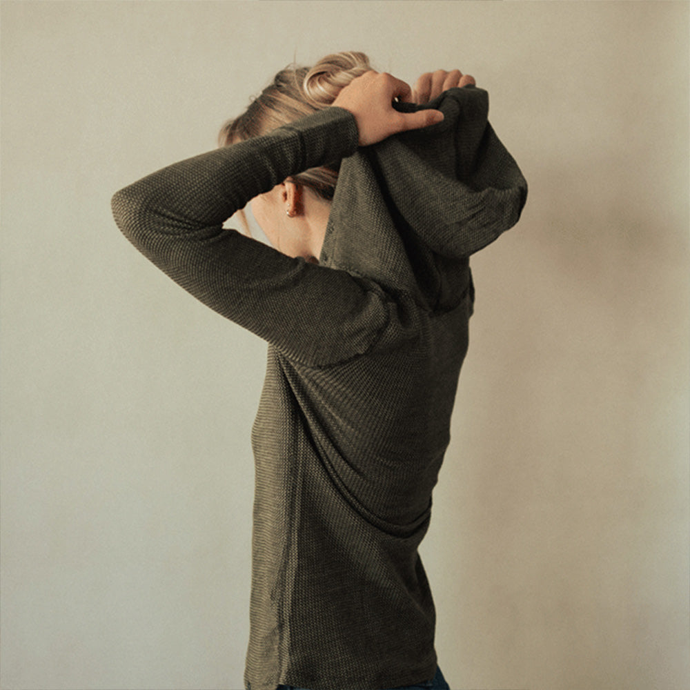 A woman wearing a green American made Duckworth merino wool waffle knit hoody.