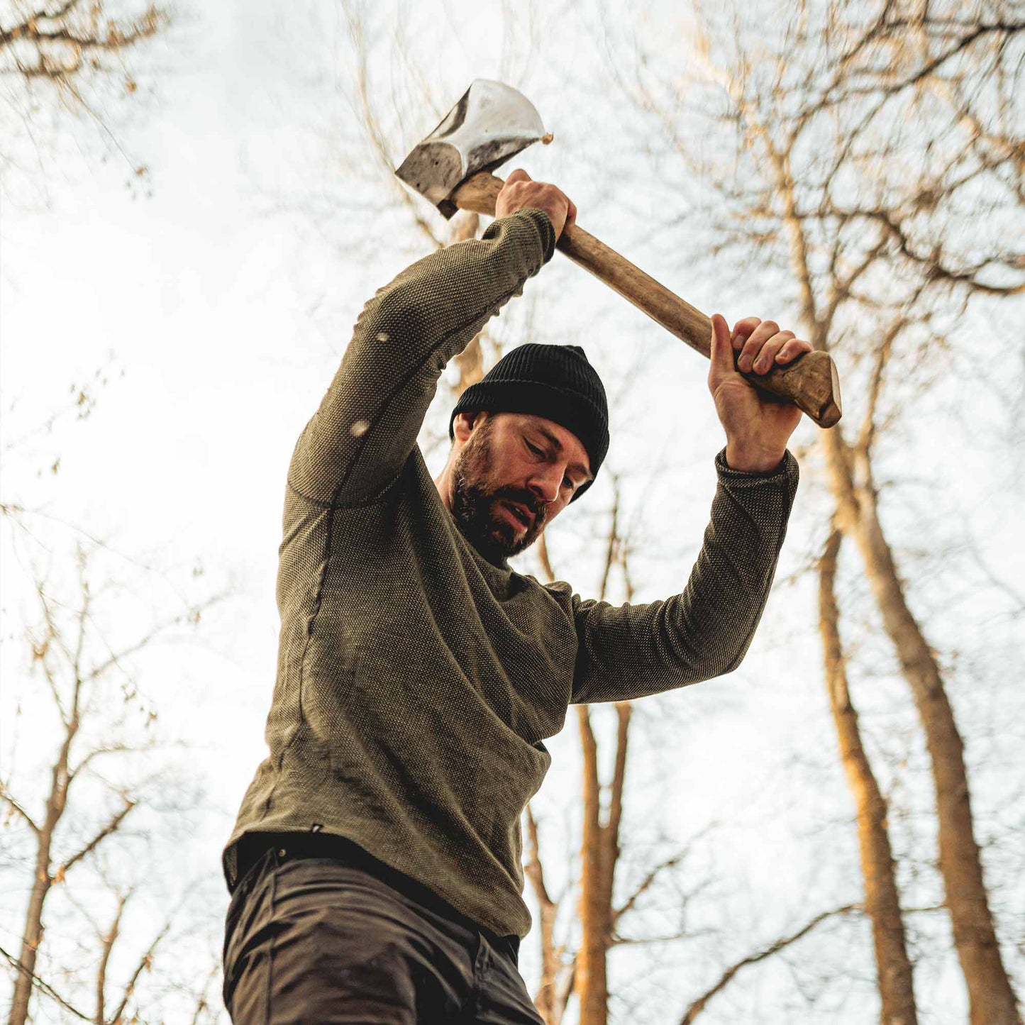 A man in Montana chopping wood in a wool shirt.